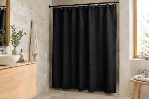 Rideau de douche textile noir suspendu dans une salle de bain aux murs de pierre claire et détails en bois blond.