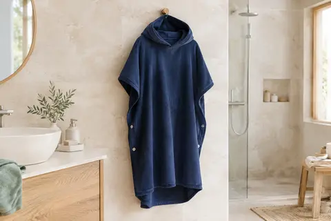 Poncho de bain adulte bleu marine à capuche suspendu dans une salle de bain lumineuse