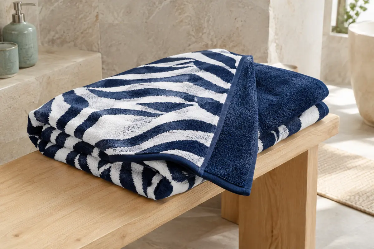 Serviette de plage en coton bleu marine et blanc, pliée pour montrer ses faces éponge et velours