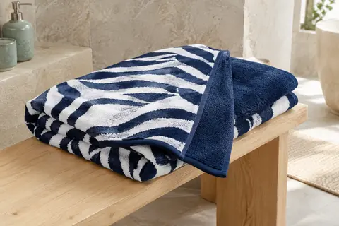 Serviette de plage en coton bleu marine et blanc, pliée pour montrer ses faces éponge et velours